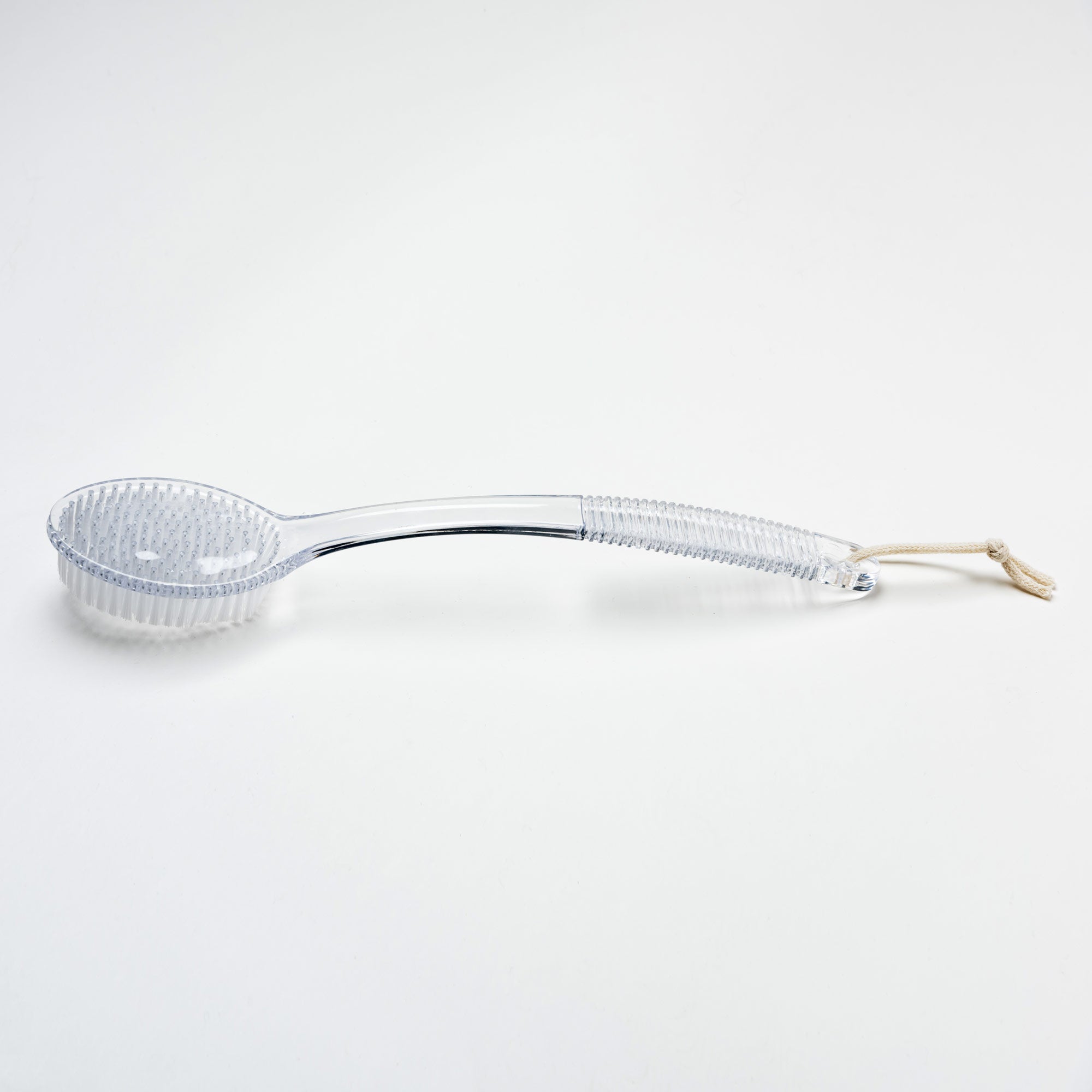 Clear glass ladle with a white handle on a light gray background. Victoria James Body Bath & Shower Brush