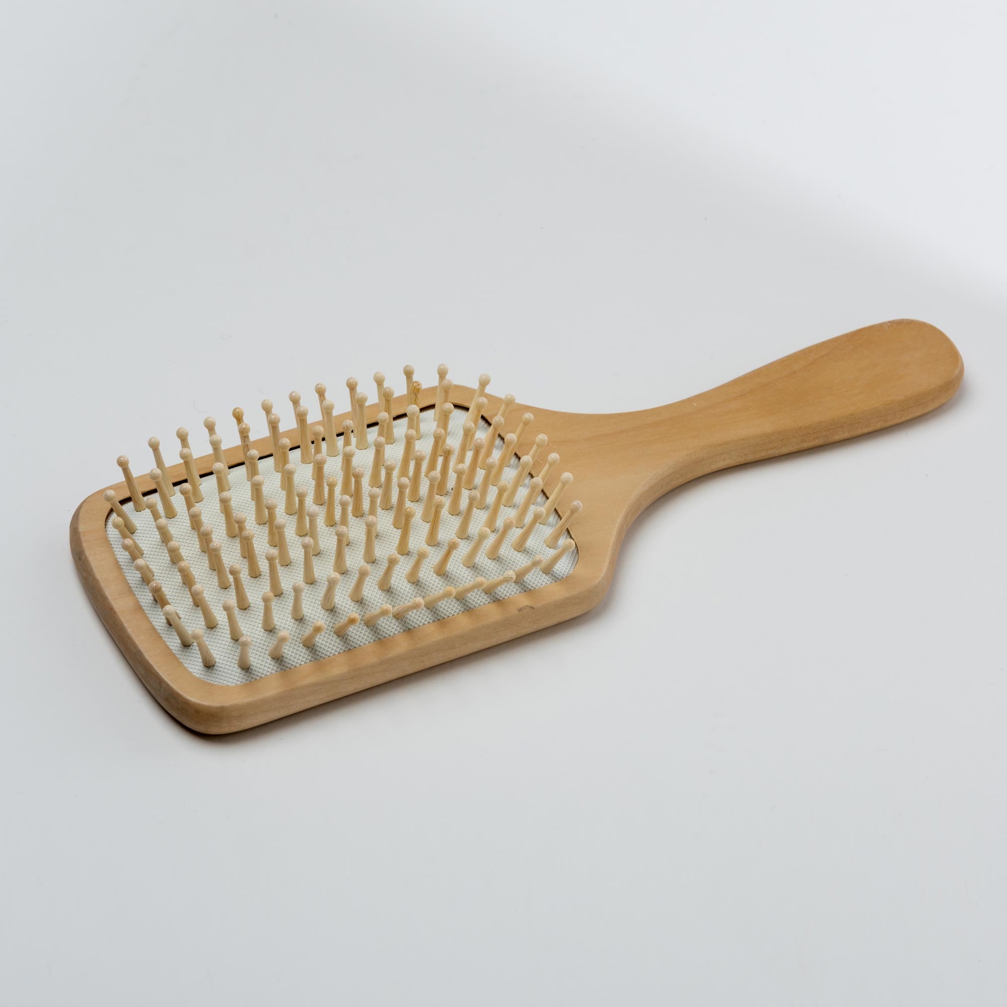 Wooden hairbrush with bristle head on a light gray background. Victoria James Wooden Paddle Hair Brush